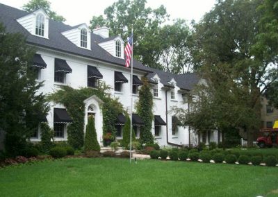 black awnings over windows of white brick home